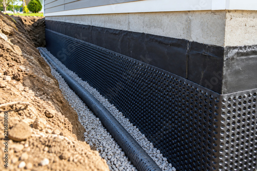 Dimple drainage board and perforated drain pipe in trench along foundation wall - exterior foundation waterproofing