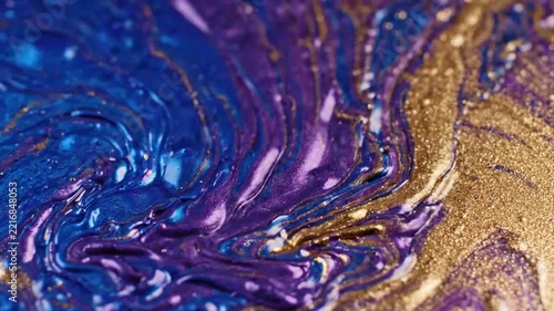 Close-up of swirling metallic blue and gold paint in motion