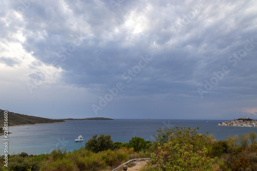 Scenic horizontal seascape of Dalmatian coast showing yacht anchored in turquoise bay near Primosten