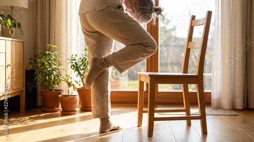 Senior woman balancing on one leg while standing in a bright home interior