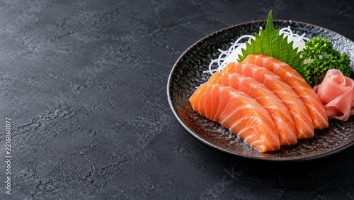 Fresh Salmon Sashimi with Pink Ginger and Green Garnish on Black Plate