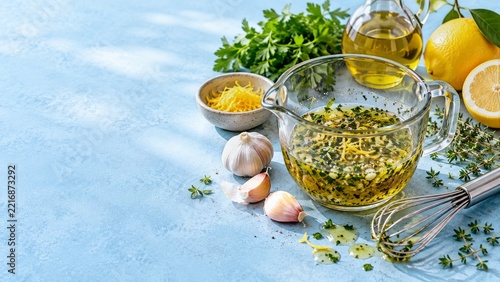 Herb and Lemon Marinade in a Glass Pitcher on a Pale Blue Counter