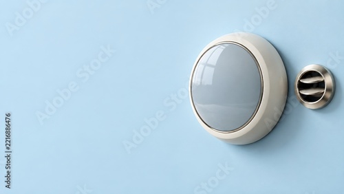 Cream Round Thermostat with a Blank Glass Face Beside a Metal Air Vent