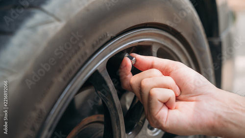 Hand removing the valve cap from a car tire