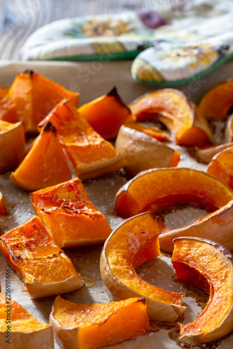 Roasted pumpkin slices on baking sheet with colorful kitchen towel.
