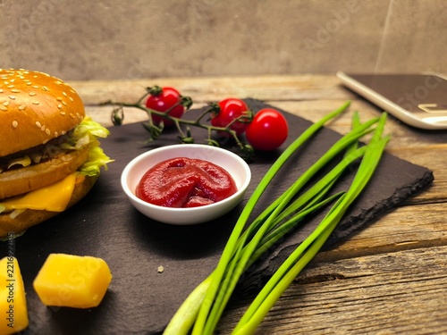greens, cheese, tomatoes with hamburger on a rustic board