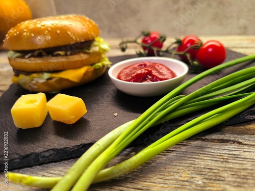 greens, cheese, tomatoes with hamburger on a rustic board