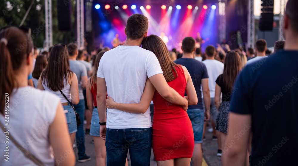 Obraz premium Romantic couple enjoying live music concert together, embracing during vibrant festival performance