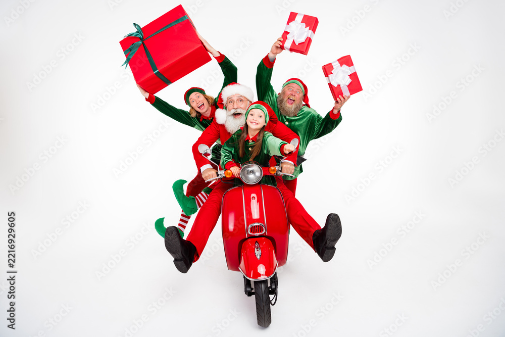 Fototapeta premium Santa and elves joyfully delivering gifts on a red scooter with a smiling child in a festive Christmas family celebration