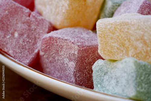 Colorful Turkish Delight Cubes Dusting with Powdered Sugar. Traditional Sweet Dessert Close-Up. Close-up macro photograph of colorful Turkish delight cubes generously coated with powdered sugar