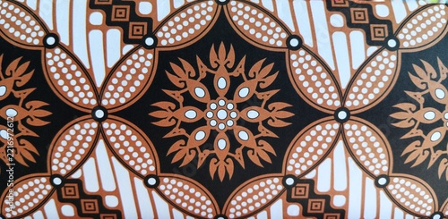 Traditional Indonesian batik inspired ornamental pattern printed on decorative gift wrapping paper, featuring geometric and floral motifs in brown, black, and white.