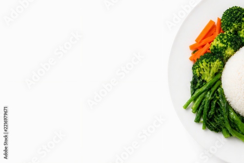 Top view of healthy food plate with steamed white rice broccoli carrots and green vegetables with copy space on white background