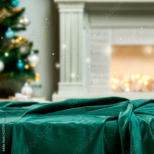 Elegant Christmas setting with clear space for product placement in the foreground and cozy festive interior in the background. Christmas tree with warm glowing lights, product mockup.
