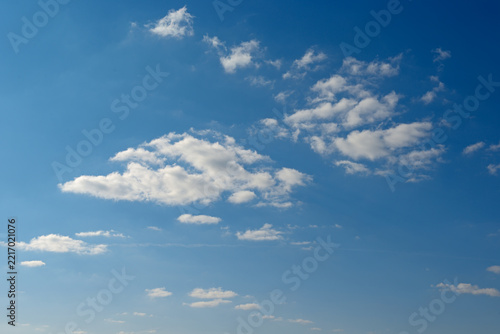 Fluffy White Clouds Floating In Clear Blue Sky During Bright Sunny Day With Ample Copy Space Background.