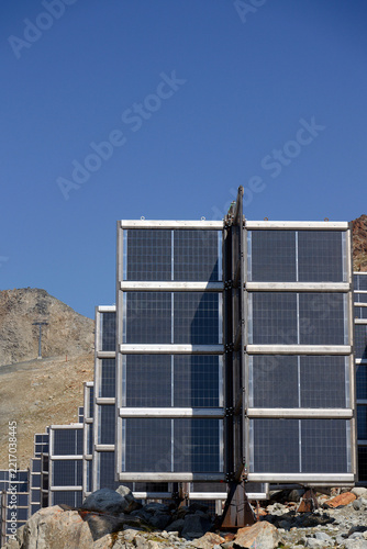 Detail of solar panels in mountains vertically mounted as four wings around central column like tree, photovoltaic plant avoid snow accumulation, future innovation energy concept