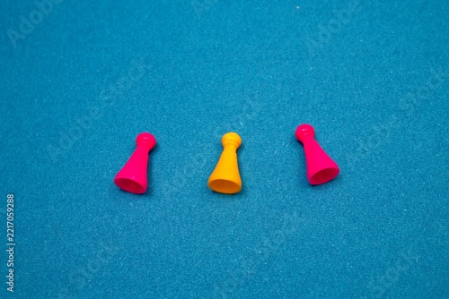 Three Colorful Board Game Pawns on Blue Textured Background