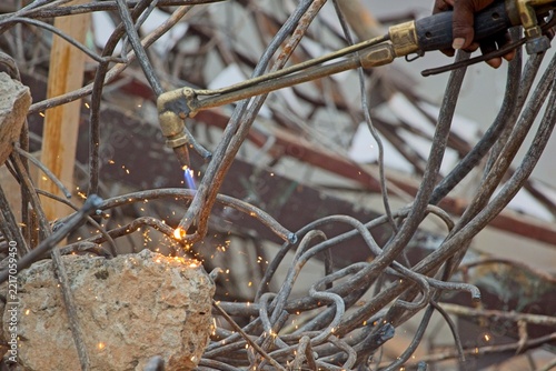 Worker Cutting Steel Rebar with Gas Torch at Demolition Site