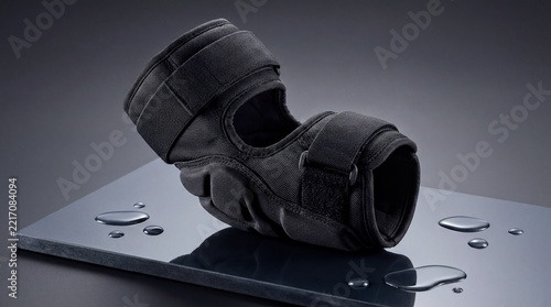 Protective elbow pad, A durable black elbow pad rests on a reflective dark surface