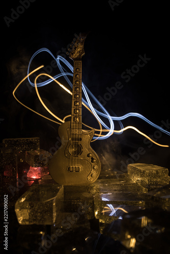Music Concept: Guitar Miniature on a Dark Background with Vivid Light, Smoke, and Fire Effects. Golden electro guitar under a Dramatic Spotlight.