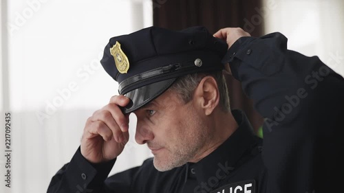 Confident policeman adjusts uniform and cap before starting his work shift
