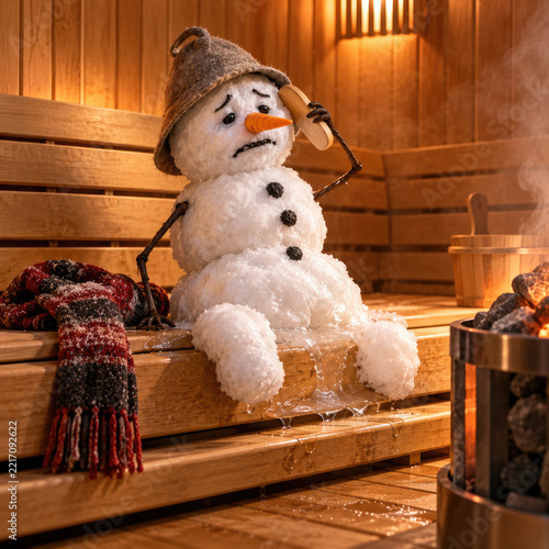 Melting snowman sits on a wooden sauna bench beside hot stones.