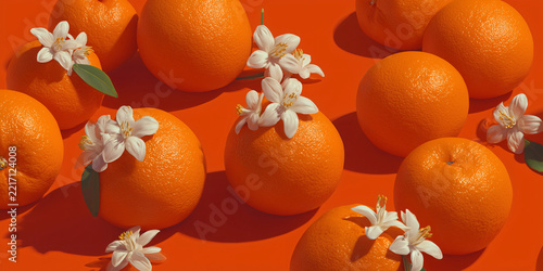 A vibrant arrangement of ripe oranges adorned with delicate white blossoms, set against a warm, striking orange background