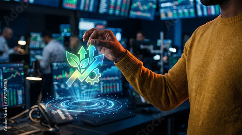 Side profile of a person in a yellow sweater interacting with a glowing holographic green leaf, arrow, and gear icon in a dark stock market trading room