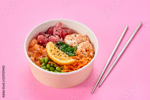 A colorful bowl of sushi with vibrant ingredients against a pink background.