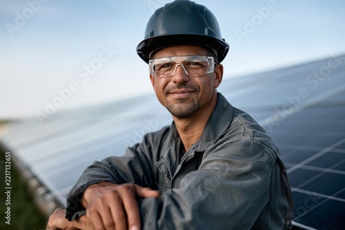 Smiling solar panel technician in hard hat and safety glasses