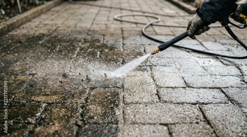 Man Using Pressure Washer on Stone Patio