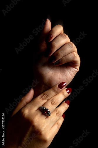 Elegant Female Hands with Burgundy Nail Polish and Vintage Ring on Black Background