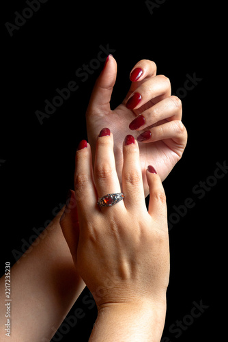 Elegant Female Hands with Burgundy Nail Polish and Vintage Ring on Black Background