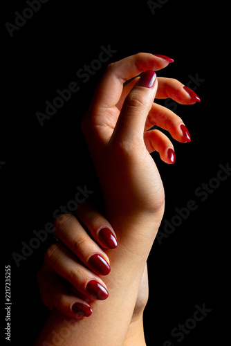 Elegant Female Hands with Burgundy Nail Polish and Vintage Ring on Black Background