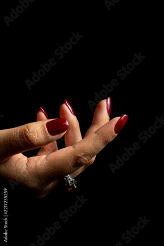 Elegant Female Hands with Burgundy Nail Polish and Vintage Ring on Black Background