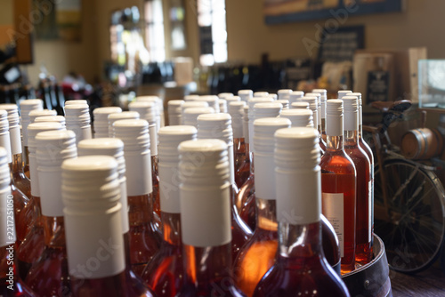 Fotografie Rose wine bottles arranged in rows on a counter inside a winery, showcasing the