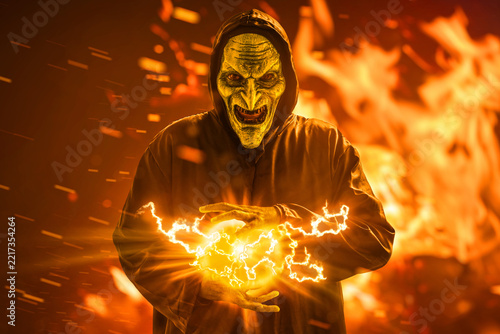 Scary witch with magic spell on fire background, Halloween theme