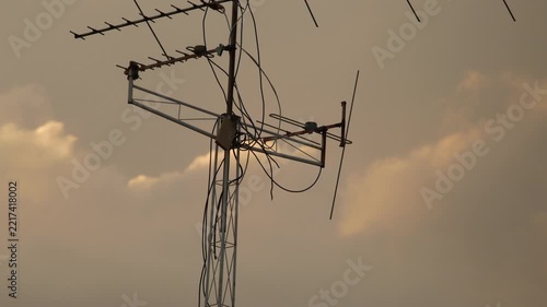Silhouette of Rooftop TV Antennas Against Vivid Orange Sunset Sky