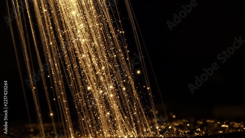 Golden light beams cascade down, sparkling like stars against a dark backdrop.
