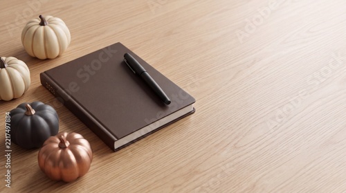 Brown 2026 planner notebook with a black pen and decorative pumpkins on a wooden desk background, featuring ample negative space on the right for autumn planning and seasonal marketing copy.