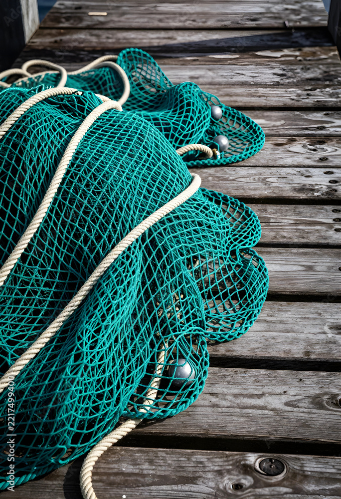 Fototapeta premium Sustainable fishing and marine conservation, commercial fishing net with weights resting on a weathered wooden pier at a harbor for maritime industry