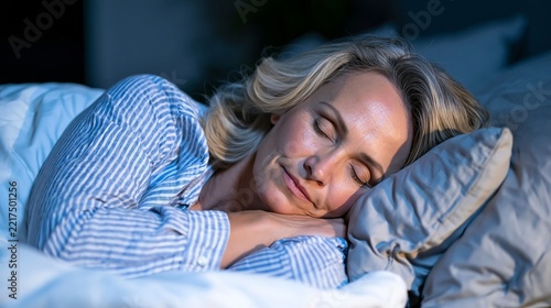 Mature blonde woman sleeping peacefully in bed with striped pajamas and soft pillows