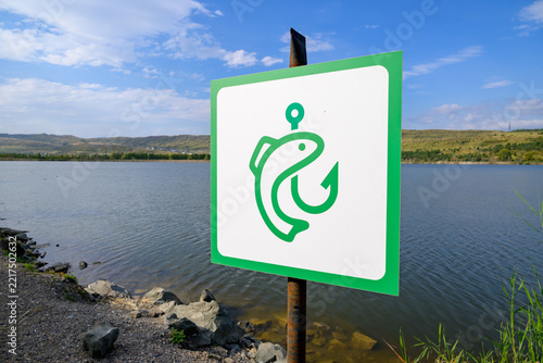 Fotografie Square sign entwined by a fish symbolizes a fishing area in a serene natural lan