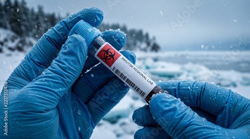 Gloved hands holding biohazard test tube against gloomy landscape.