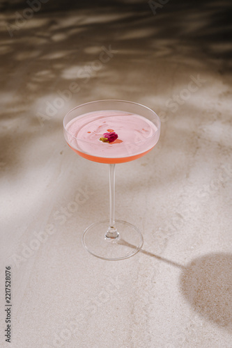 Pink cocktail in coupe glass with rosebud garnish