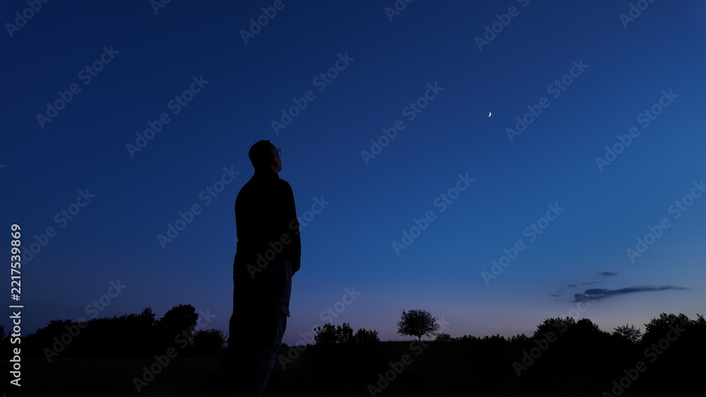 Fototapeta premium Silhouette of a person in nature observing night sky, Moon, stars and planets from a remote location.