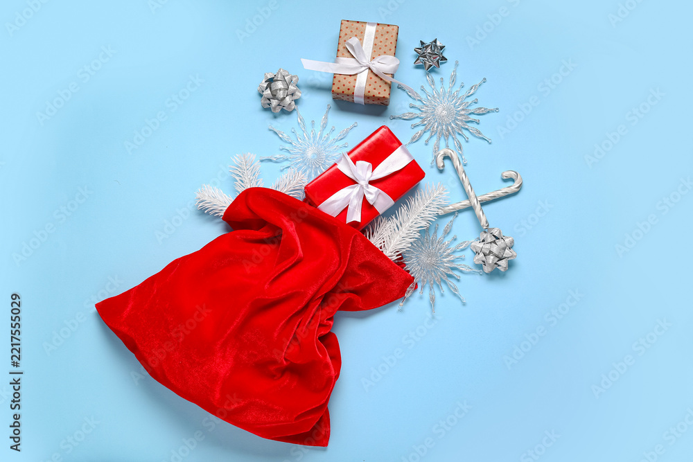 Fototapeta premium Santa bag with gift boxes, decorative snowflakes and candy canes on blue background
