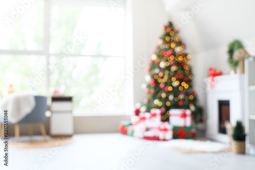 Blurred view of light living room with Christmas tree, presents and fireplace