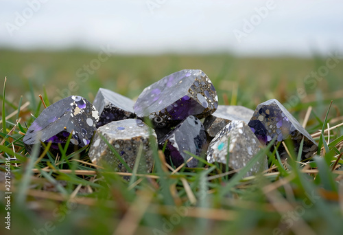 Geology and mineralogy exploration, rare purple gemstone crystals with unique mineral inclusions resting in natural green grass field outdoor setting