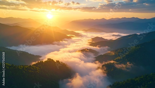 Sunrise over mountains shrouded in mist, with the golden sunbeams illuminating the scene