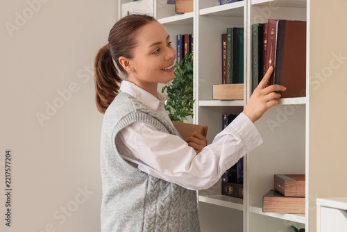 Education and lifelong learning, young woman choosing a book from a library s...